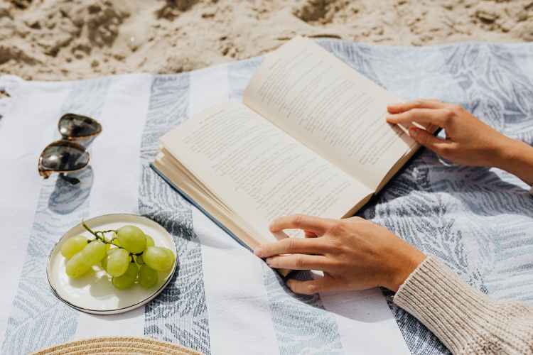 Person reading book on the beach